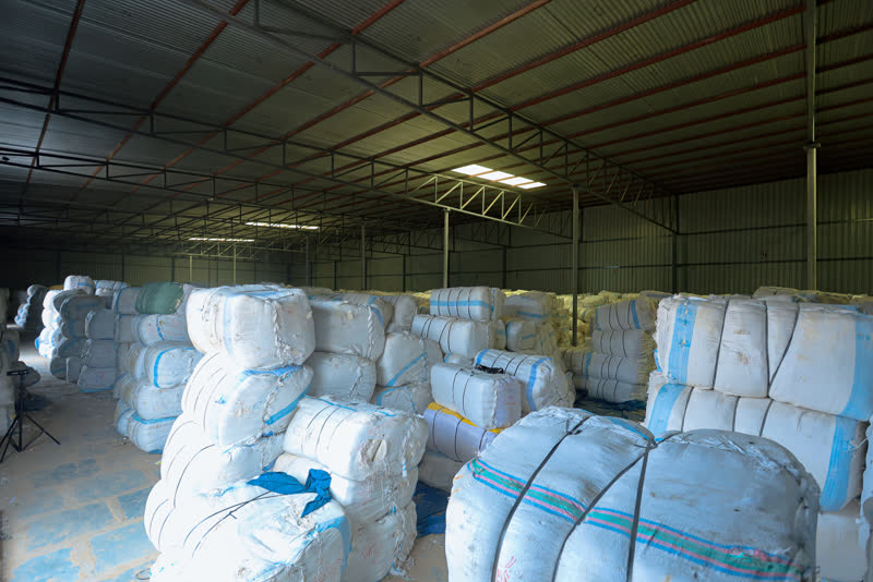 Cloth bales stacked along the warehouse aisle.