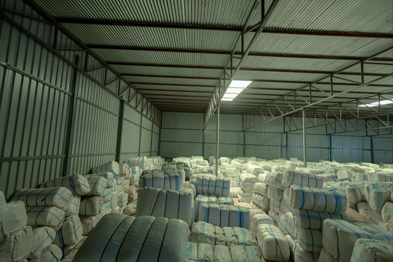 Cloth bales filling the warehouse under the skylights.